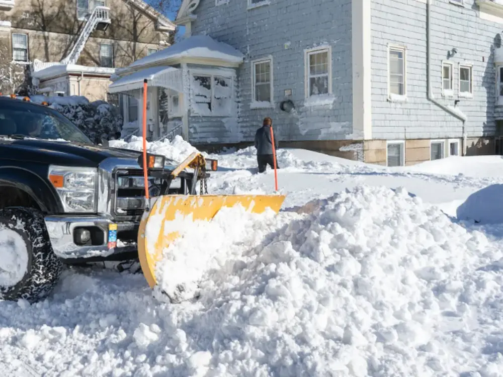 Plow truck clearing a residential driveway after a storm